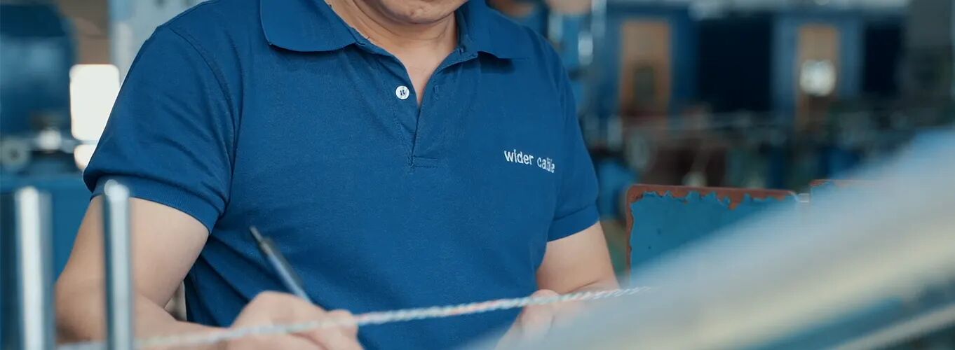 A Wider Cable technician inspecting an Ethernet cable on the production floor